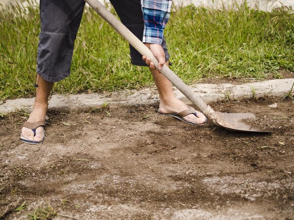 Mann bereitet mit einer Schaufel den Boden für Gartenarbeiten vor.